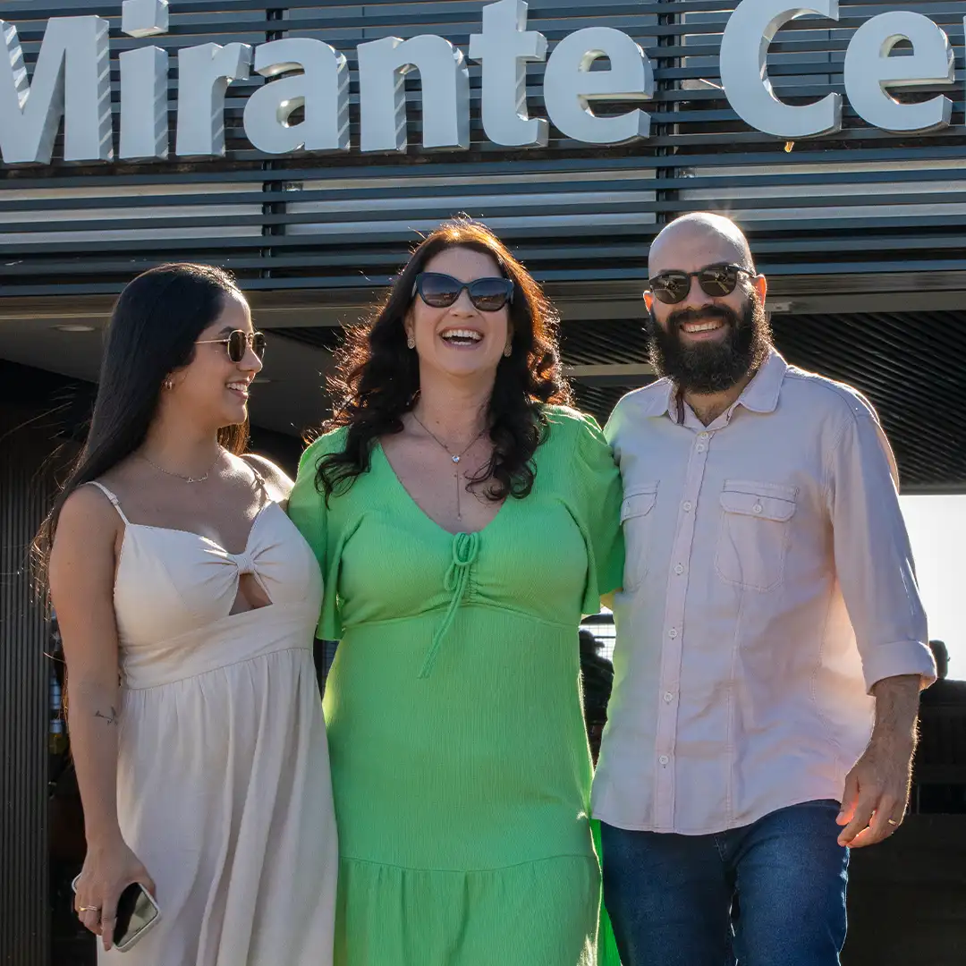 Um homem e duas mulheres posando para foto e sorrindo no Mirante Central da Usina Hidrelétrica de Itaipu, em Foz do Iguaçu