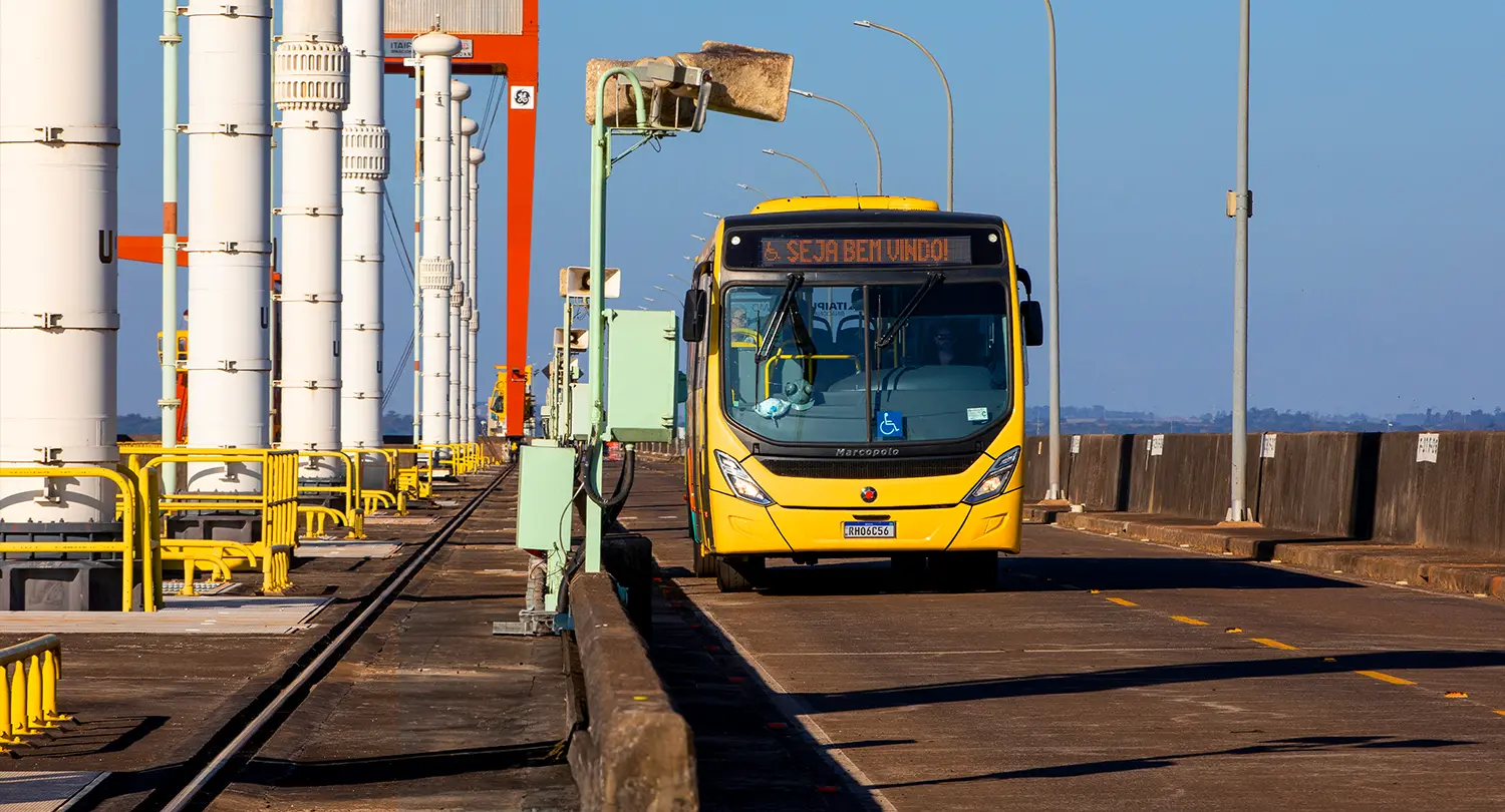 Ônibus amarelo de passeio, passando pelo topo da barragem da Usina Hidrelétrica de Itaipu, localizada em Foz do Iguaçu.
